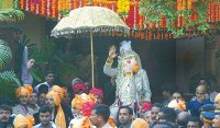 عريس يرتدي الملابس التقليدية و يغطي وجهه بعقود من الزهور خلال مراسم الزواج 